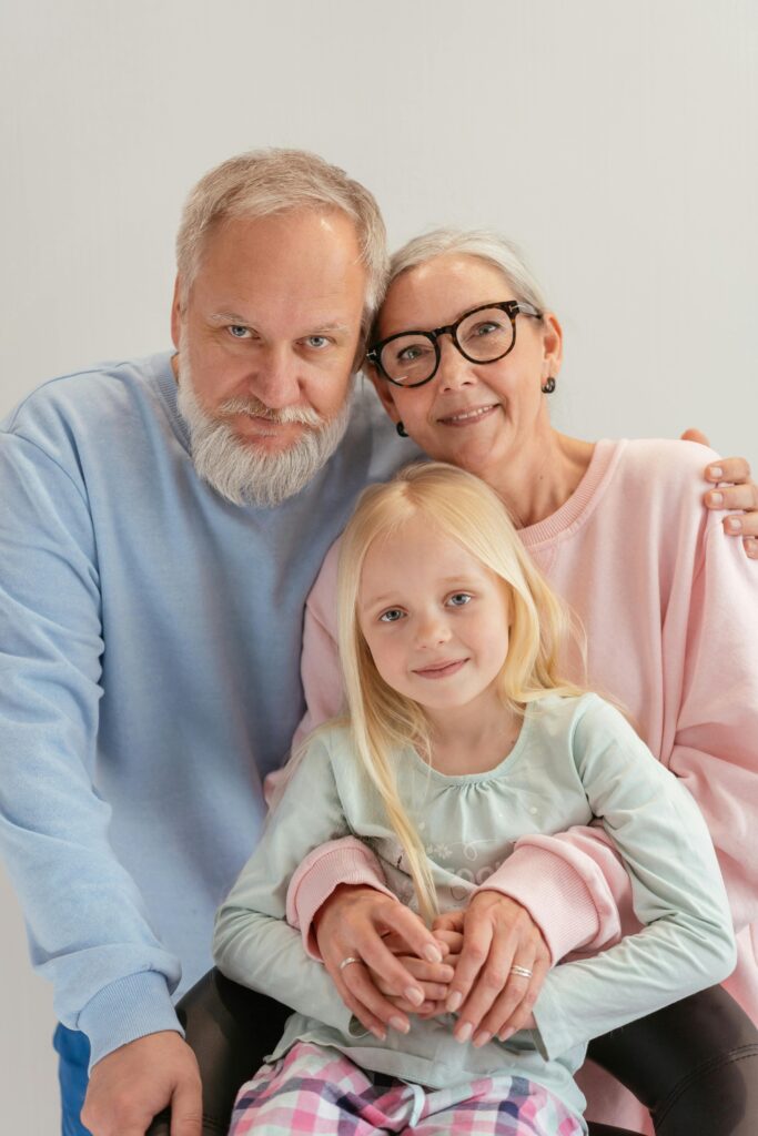 Cheerful grandparents posing with their granddaughter in a cozy indoor setting.